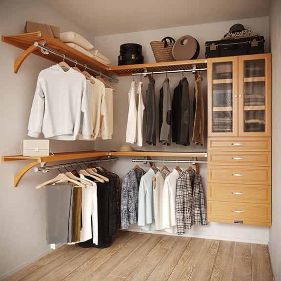 Honey Maple L Shaped walk in closet organizer with 5 drawers and doors, clothes and hanging in a primary bedroom closet.