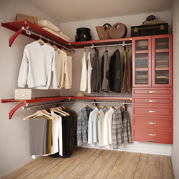 Red Mahogany L Shaped walk in closet organizer with 5 drawers and doors, clothes and hanging in a primary bedroom closet.