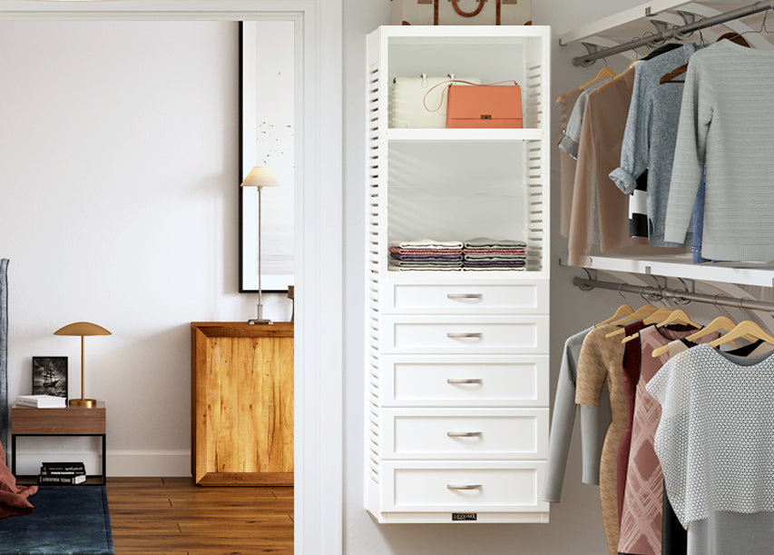 white storage tower with drawers and shelves in master bedroom closet with clothes hanging